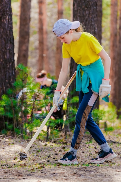 Little girl picks up trash in woods on summer day Ecological action Child cleanses nature of pollution and trash