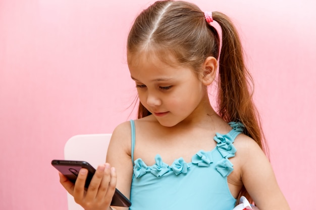 Little girl on a pink background talking on the phone