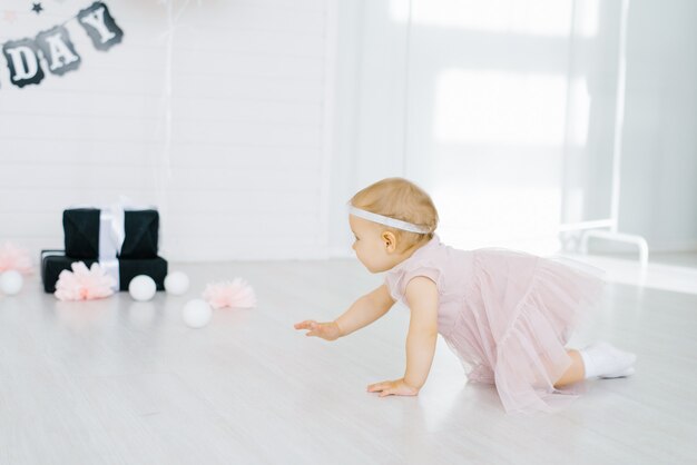 little girl in a pink dress crawls on the floor