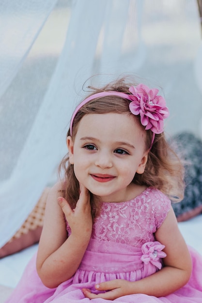 маленькая девочка в розовом платье веселится в саду
