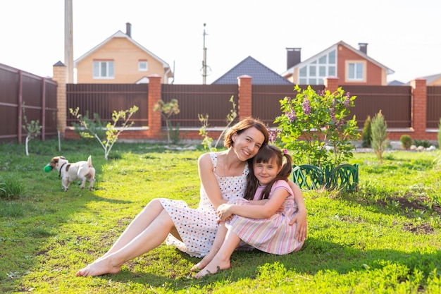 草の上に座っている庭で母親とピンクのドレスを着た少女