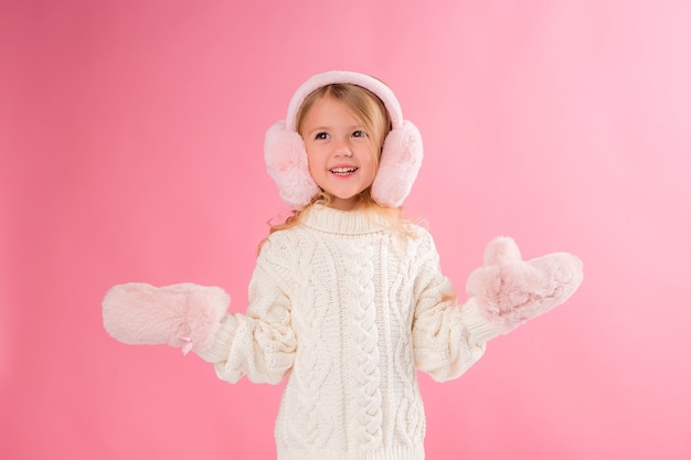 little girl in pink mittens and headphones on a pink wall