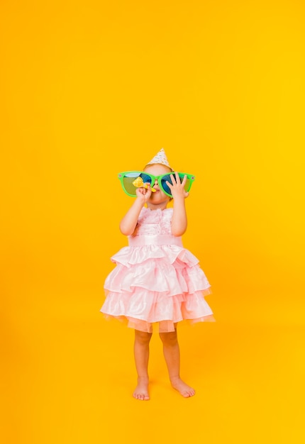 A little girl in a pink puffy dress on a yellow background