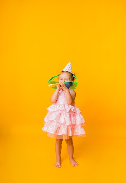 A little girl in a pink puffy dress on a yellow background