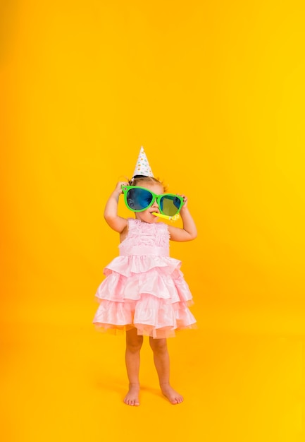 A little girl in a pink puffy dress on a yellow background