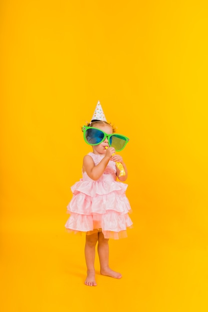 A little girl in a pink puffy dress on a yellow background