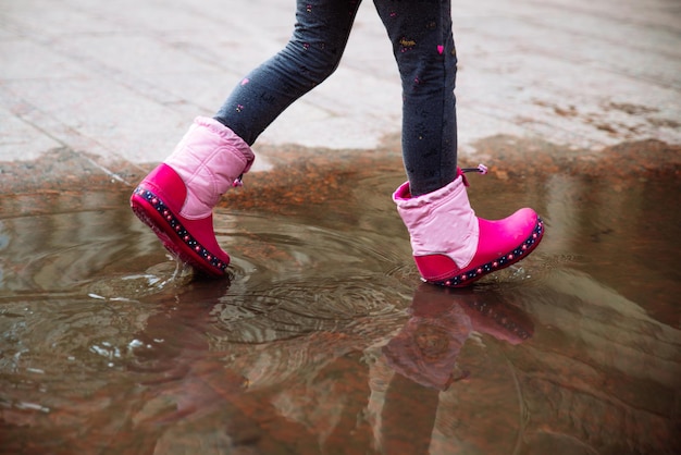 水たまりのピンクのゴム長靴の少女。