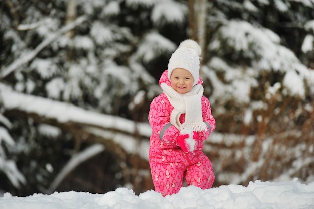 A little girl in a pink suit walks outside in winter.