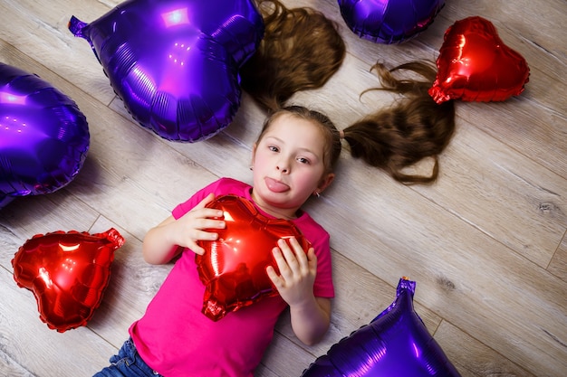 Little girl in pink T-shirt plays with balloons