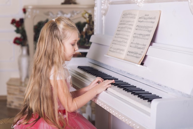 Little girl play on piano in dress