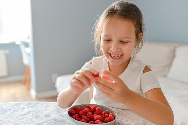 The little girl played with raspberries on her fingers