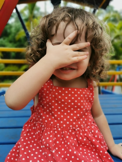 Маленькая девочка играет, закрывая лицо рукой