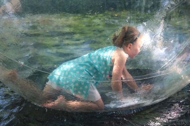 Little girl playing for a drive in transparent sphere Kid playing on water Happy childhood