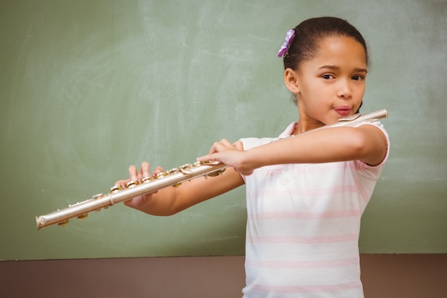 Little girl playing flute in classroom