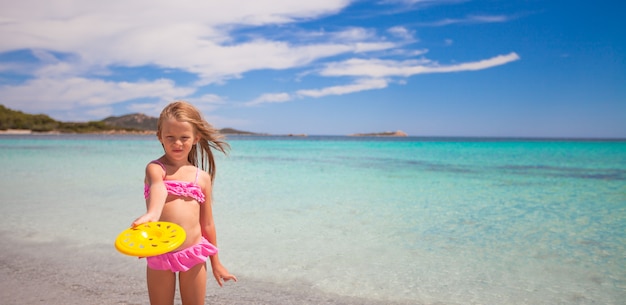 Bambina che gioca frisbee durante la vacanza tropicale nel mare