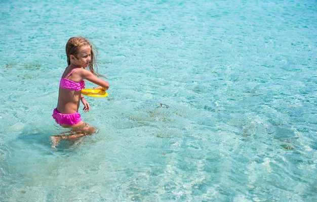 Little girl playing frisbee during tropical vacation in the sea