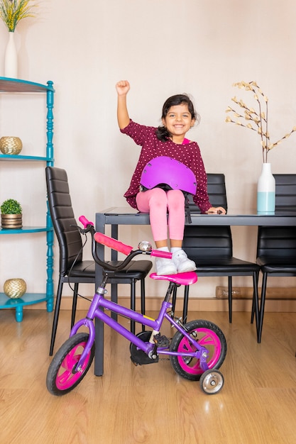 Little girl playing her bicycle in the living room of the apartment during quarantine