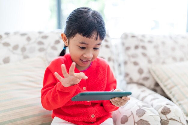 家で携帯電話で遊ぶ小さな女の子