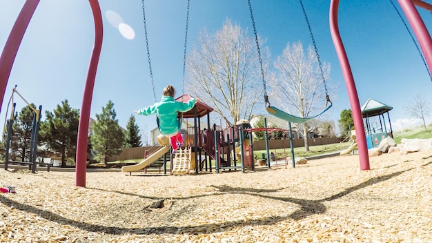 Bambina che gioca sul parco giochi per bambini all'aperto in periferia.