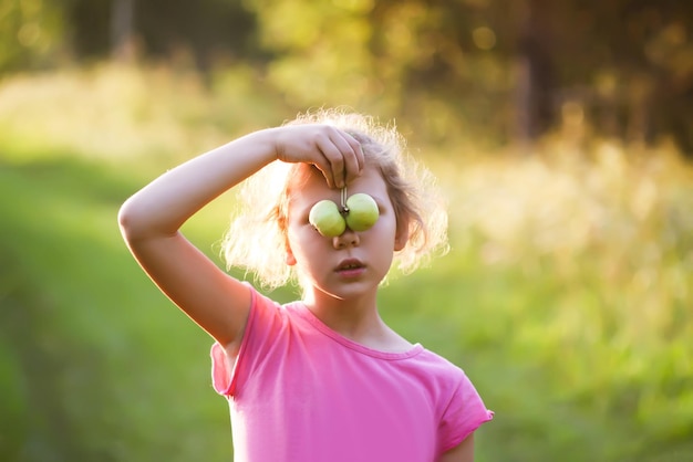 Little girl playing peek a boo with green apples