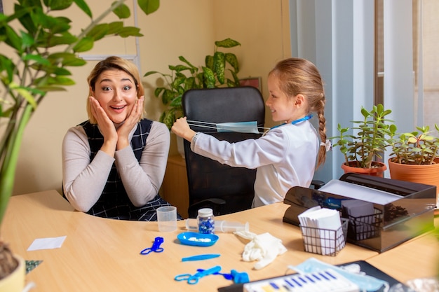 Little girl playing pretends like doctor for woman