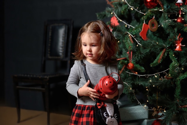 Little girl playing in the room near the holiday tree