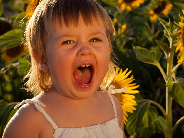 Little girl playing in sunflower field.