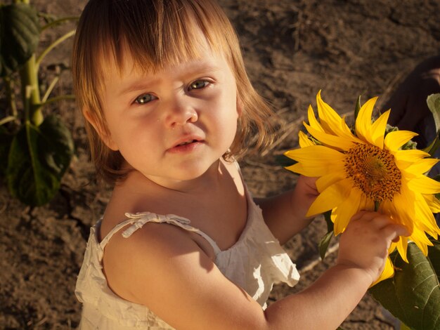 Little girl playing in sunflower field.