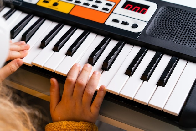 A little girl playing the synthesizer the concept of teaching children music hands closeup