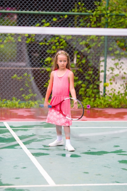 Маленькая девочка играет в теннис на корте