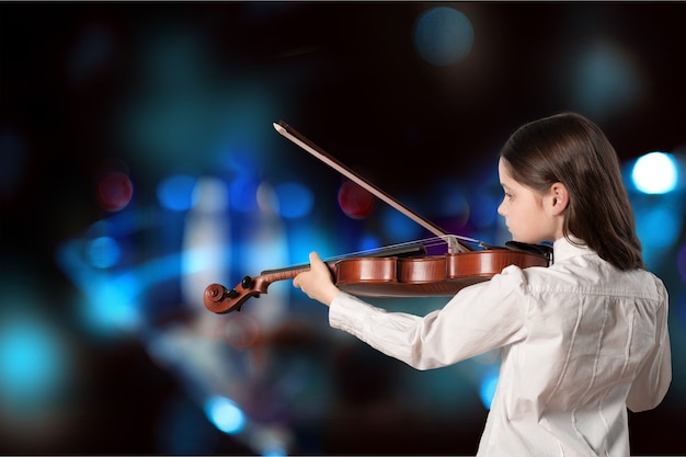 Little girl playing violin on blurred background