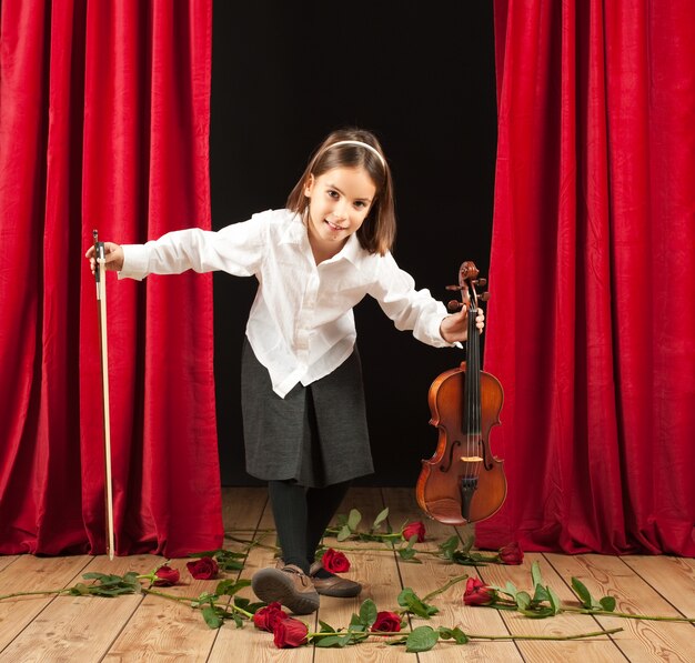 Little girl playing violin on stage theater