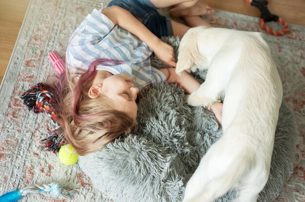 写真 自宅でゴールデンレトリバーの子犬と遊ぶ少女 自宅の友達