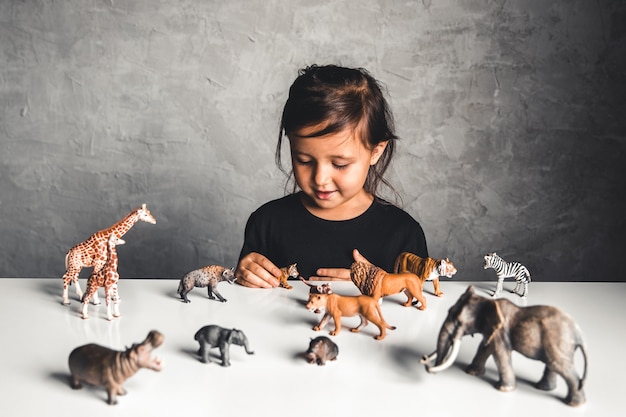 Photo little girl playing with animal toys in playroom