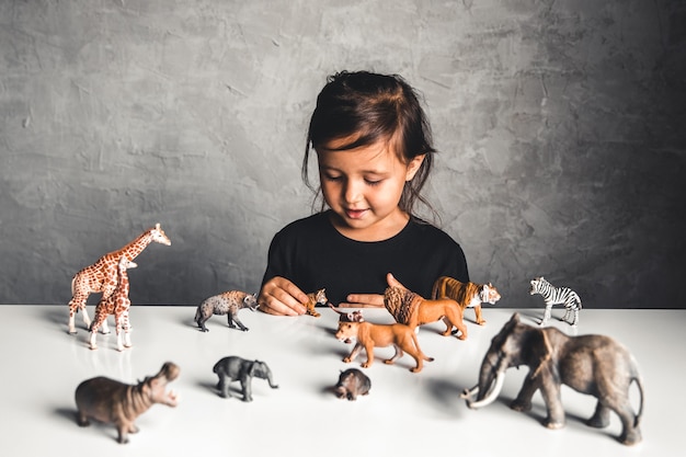 Little girl playing with animal toys in playroom