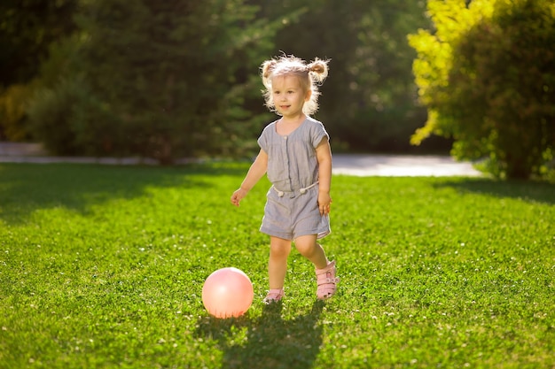 Photo little girl playing with a ball in the park