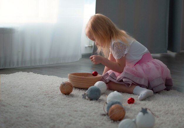 Little girl playing with Christmas toys near the tree. Attributes of the decor. selective focus.