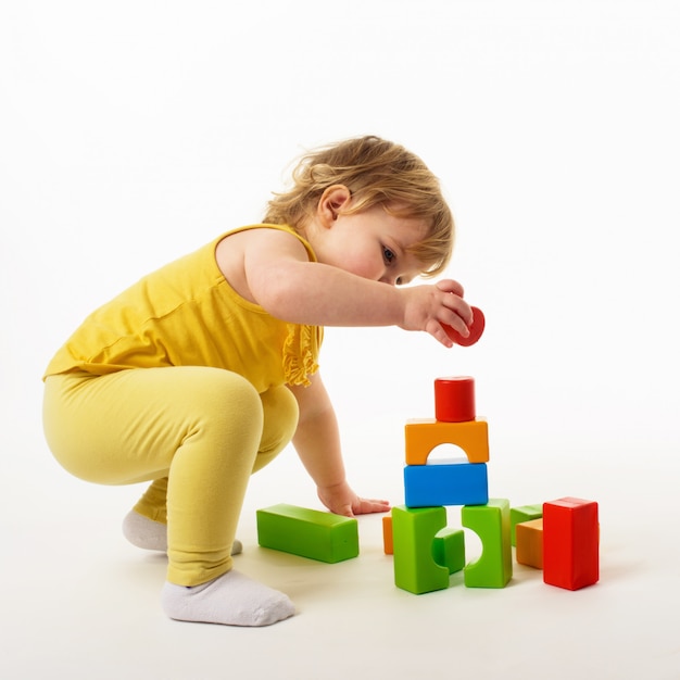 Little girl playing with colorful toy blocks