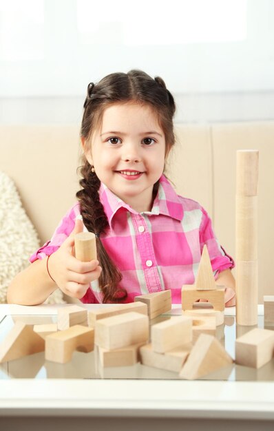 Little girl playing with cubes on home interior background