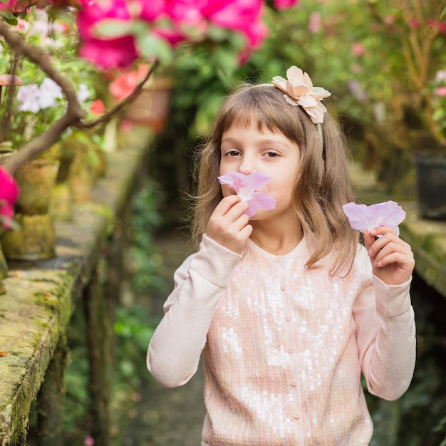 温室で花で遊ぶ少女ツツジシャクナゲの花植物園フラワーショップ家族農業のコンセプト