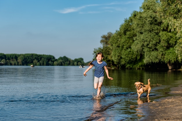 Bambina che gioca con il suo cane nel fiume