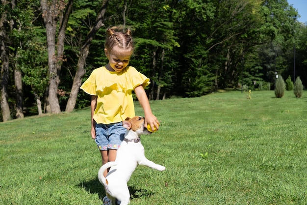 Little girl playing with her pet dog Jack Russell Terrier in park