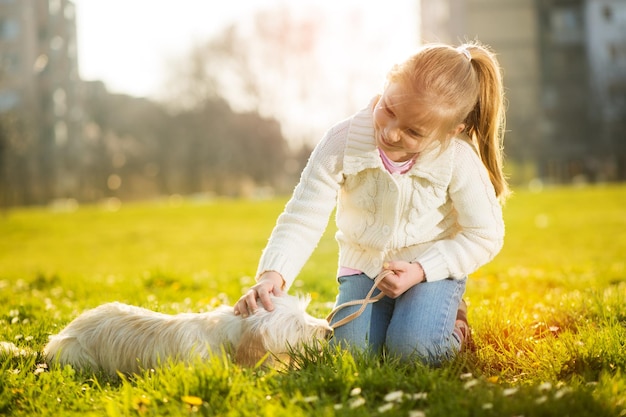 Little girl playing with her puppy dog in the park