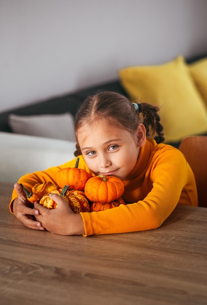 Little Girl Playing With a Pumpkin emotional portrait at home Halloween party concept Vertical