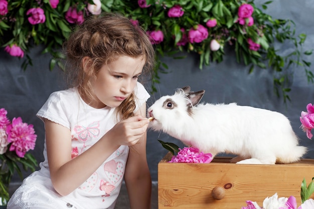 사진 진짜 토끼를 가지고 노는 어린 소녀. 부활절에 아이 흰색 토끼. 애완 동물 동물을 먹이 유아 아이. 아이들과 애완 동물이 놀아요. 동물과 아이들을위한 재미와 우정.