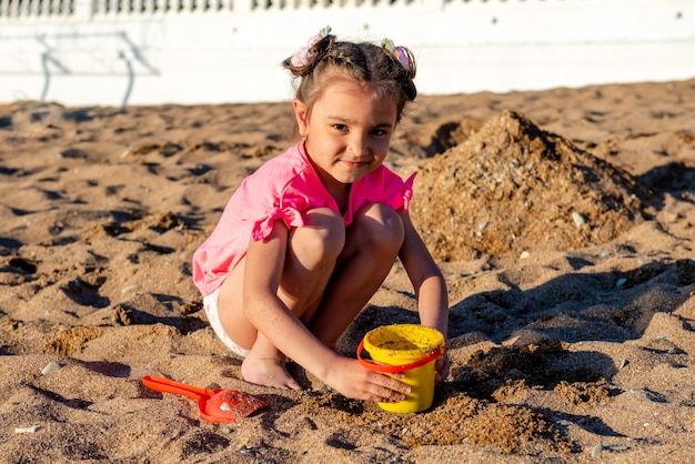 Bambina che gioca con la sabbia sulla spiaggia