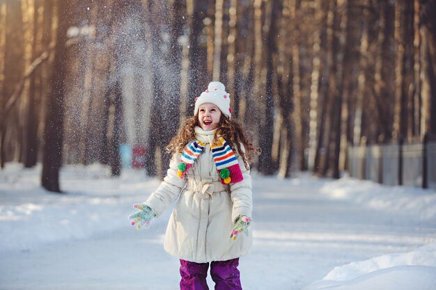 小さな女の子が雪で遊んで。