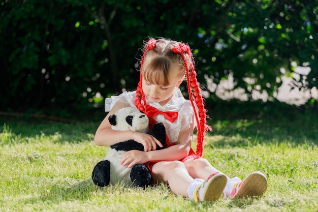 여름에 공원에서 장난감 팬더를 가지고 노는 어린 소녀. 고품질 사진