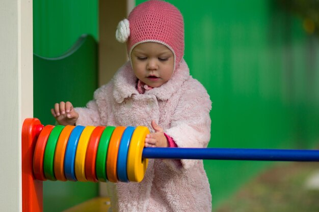 外の木のおもちゃのカウンターで遊ぶ少女