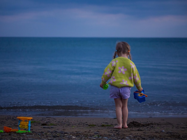 little girl plays on the beach in the evening